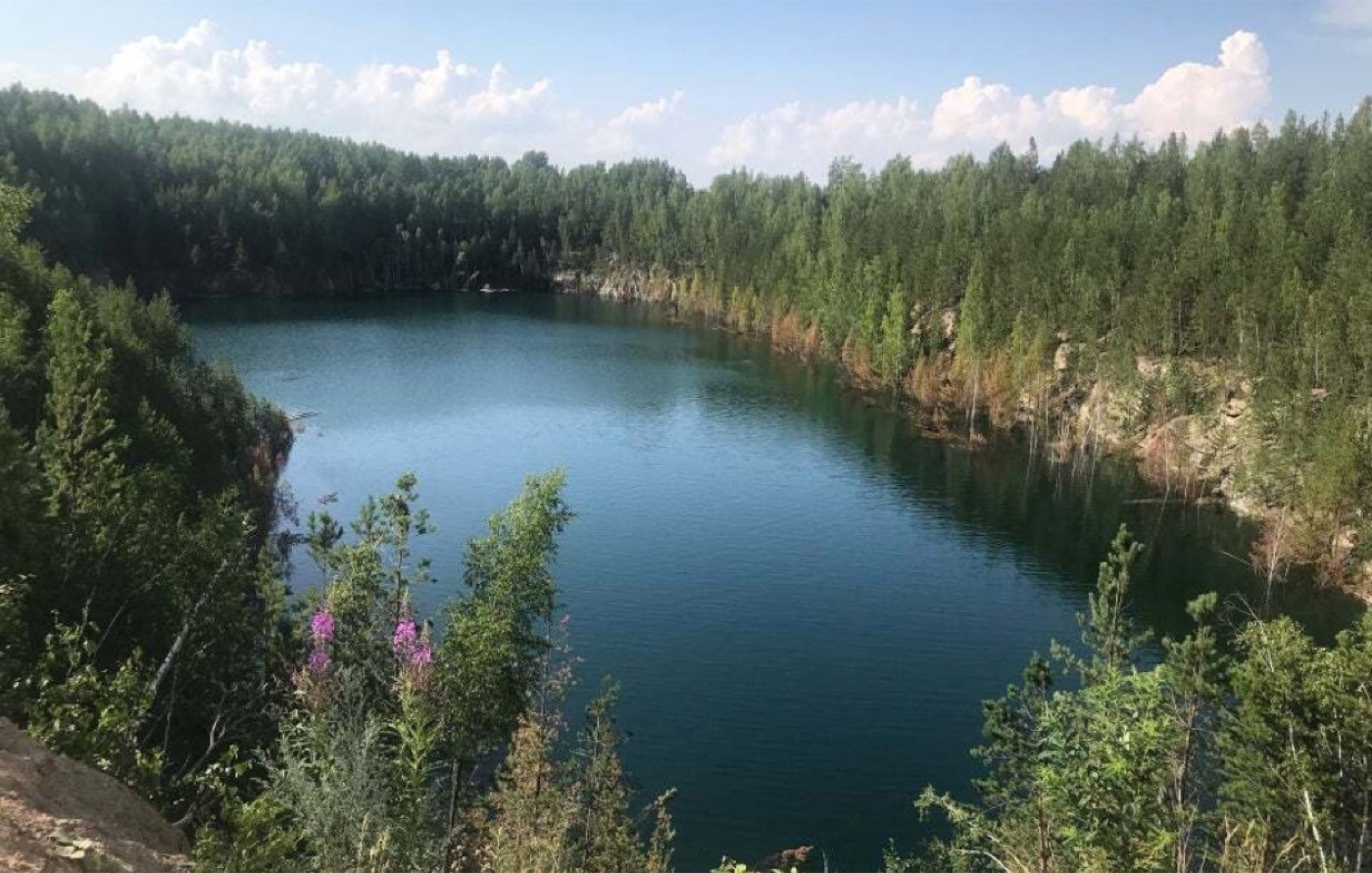 Затопленный карьер с бирюзовой водой среди леса